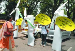 Activists of the Greenpeace stand with placards and structures of windmills outside Sonia Gandhi's residence, urging the young MPs to lead the ministry of new & renewable energy, in New Delhi on Thursday