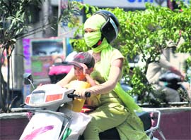 A woman protects herself from the scorching sun while driving a two-wheeler in Dehradun on Thursday.
