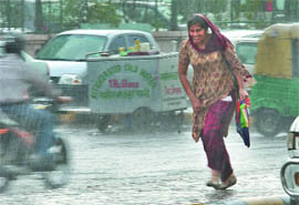 A woman rushes for shelter during a sudden downpour that relieved the Capital from the scorching heat on Friday.