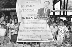 Internally displaced Sri Lankan people wait behind a welcome banner for a visit by United Nations Secretary-General Ban Ki-moon at Menik Farm refugee camp in Cheddikulam on Saturday.