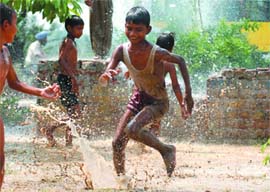 A DRAIN ON RESOURCES: Children play in the water spilling from a broken pipe of the Delhi Jal Board near Nizamuddin Bridge in New Delhi on Sunday.