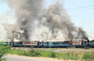 The Jammu-Tawi Express burns after it was set afire by mobs protesting against the death of their religious leader in Jalandhar on Monday.