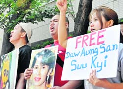 Myanmar citizens living in Japan hold portraits of Aung San Suu Kyi as they shout slogans in front of the Myanmar embassy in Tokyo 