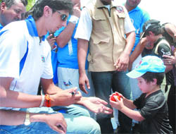 A little boy gives a ball to cricketer Ishant Sharma for his autograph during a function at Modern School in New Delhi on Wednesday.