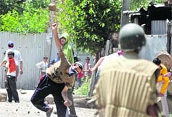 A protester throws a stone at a security personnel in Srinagar on Wednesday during a demonstration over the death of a youth. 