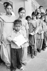 Schoolchildren stand in a queue at the mini-secretariat waiting for their turn to submit documents for caste certificates in Karna