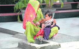 A woman makes her daughter drink water at a roadside tap in Dehradun.