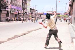A protester throws a brick towards policemen in Srinagar on Monday