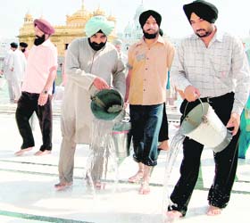 Devotees pour water on the floor of the Golden Temple to keep it cool