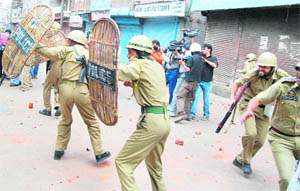 Policemen duck for cover on being attacked with stones during a protest in Srinagar on Friday over the death of two women in Shopian a few days ago.