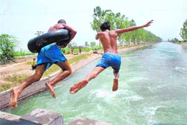 THE BIG LEAP: Two boys jump into a canal to beat the heat in Karnal on Sunday .