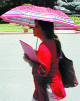 A girl at Parliament House in New Delhi uses umbrella to save herself from the scorching heat on Monday.