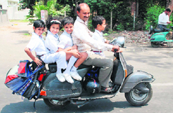 A scooter rider violates traffic norms by driving without a helmet and carrying four children in Jammu.