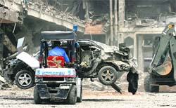 A man removes a destroyed vehicle at Pearl Continental Hotel in Peshawar on Wednesday. 