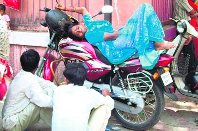 A patient rests on a motorcycle outside the Doon Hospital.