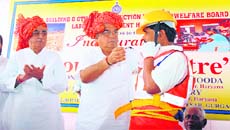 Chief Minister Bhupinder Singh Hooda presents a safety kit to a construction worker at a function organised to mark World Day against Child Labour at the IMT, Manesar, in Gurgaon on Friday.