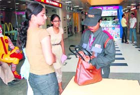 A woman security guard checks the purse of a girl at a mall in Ludhiana