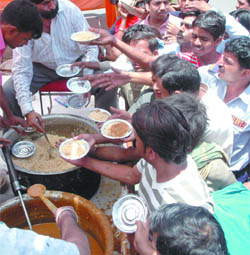 Devotees distribute food on the martyrdom day of the fifth Sikh Guru Arjan Dev in New Delhi on Tuesday.