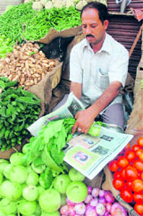 A shopkeeper uses a newspaper to wrap vegetables in Jammu.