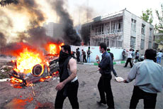 Protesters burn a car and attack a building of a pro-government militia base near a rally supporting leading opposition presidential candidate Mir Hossein Mousavi in Tehran on Monday.