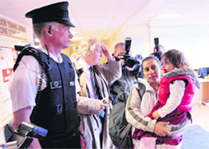 Romanian people arrive with a police escort to a Belfast City Leisure centre, Northern Ireland, on Wednesday. More than 100 Romanians have been moved @@to safer places after mounting racist attacks in the city of Belfast forced 