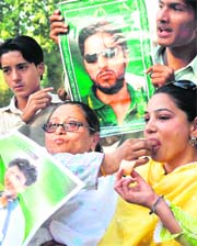 Pakistani cricket fans carry posters of the national cricketers as they distribute sweets to celebrate in Lahore on Monday.