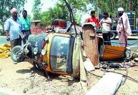 Passers-by look at the mangled remains of the auto-rickshaw in Amritsar