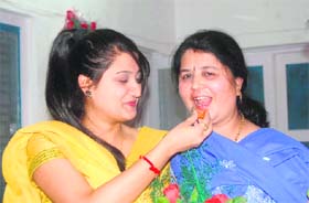 Daughter of Ramesh Pokhriyal Nishank offers sweets to her mother at their residence in Dehradun