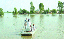 Residents draw a boat to their houses in flooded Giddarpindi village last year.