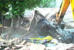 A JCB machine demolishes a kiosk during an anti-encroachment drive in Ludhiana.