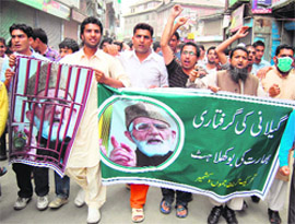 Supporters carry posters with Geelanis picture during a strike in protest against his detention in Srinagar on Friday.