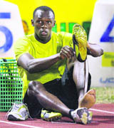 Usain Bolt of Jamaica puts on his track shoes before the start of Mens 100 meter heat at the Jamaican Athletics National Championships in Kingston on Friday.