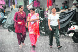 Girls enjoy the seasons first rainfall in Dehradun on Sunday.