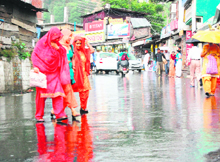 Commuters running for shelter at Kotwali Bazaar in Dharamsala as rain lashed the region, ending the long dry spell on Sunday.