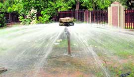 A stone placed on top of an open pipe to stop the flow of water from it at a park in Gurgaon.