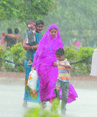 A family enjoys the first monsoon rain at India Gate in New Delhi on Tuesday.