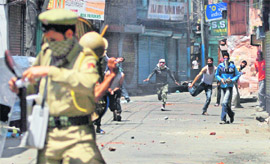 Youths pelt security personnel with stones during a protest in Srinagar on Wednesday. 