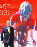 Prince Albert II of Monaco walks past a poster announcing the July 4 Tour de France cycling race