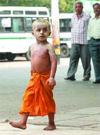 A kid smears his face and shoulders with mud to protect himself from the sun in New Delhi