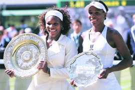 Serena Williams (L) and Venus Williams hold up their trophies after their womens final match on Saturday. 