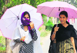 Two girls take cover under an umbrella to protect themselves from the scorching heat on the Kurukshetra University campus in Kurukshetra on Monday.