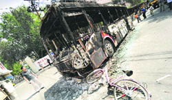 A man stands next to the burnt wreckage of a bus in a street in Chinas far west Xinjiang province on Monday.