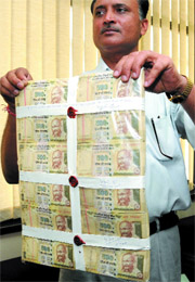 A Delhi police personnel shows fake currency notes  seized from five persons in New Delhi 