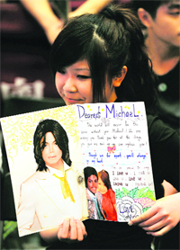 A fan of late pop singer Michael Jackson carries a card during a farewell memorial in Hong Kong on Tuesday. Devoted fans of Jackson across Asia said farewell to the King of Pop on Tuesday, singing his greatest hits, watching videos and gathering for a late-night viewing of the memorial in Los Angeles.