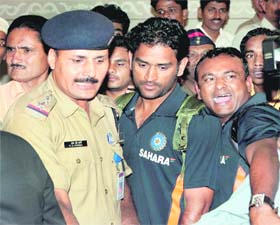 MS Dhoni is escorted by security personnel at the Chatrapati Shivaji International Airport in Mumbai as Team India returned on Tuesday night after winning the series against West Indies by 2-1