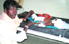 Balesar, a migrant labourer, attends to his 3-year-old son Dukha at a private hospital in Nakodar.