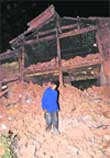 A man stands on the debris of a collapsed house in Yaoan County in southwest Chinas Yunnan Province