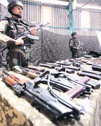 Troops stand guard near seized arms and ammunition during a press conference at an Army garrison in Kupwara