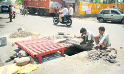 Workers cover a manhole in Shastri Nagar in Jammu.