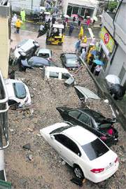 Cars partially buried in soil and gravel after flood waters swept them off a street following heavy rain in Busan, southeast of Seoul, on Thursday. 